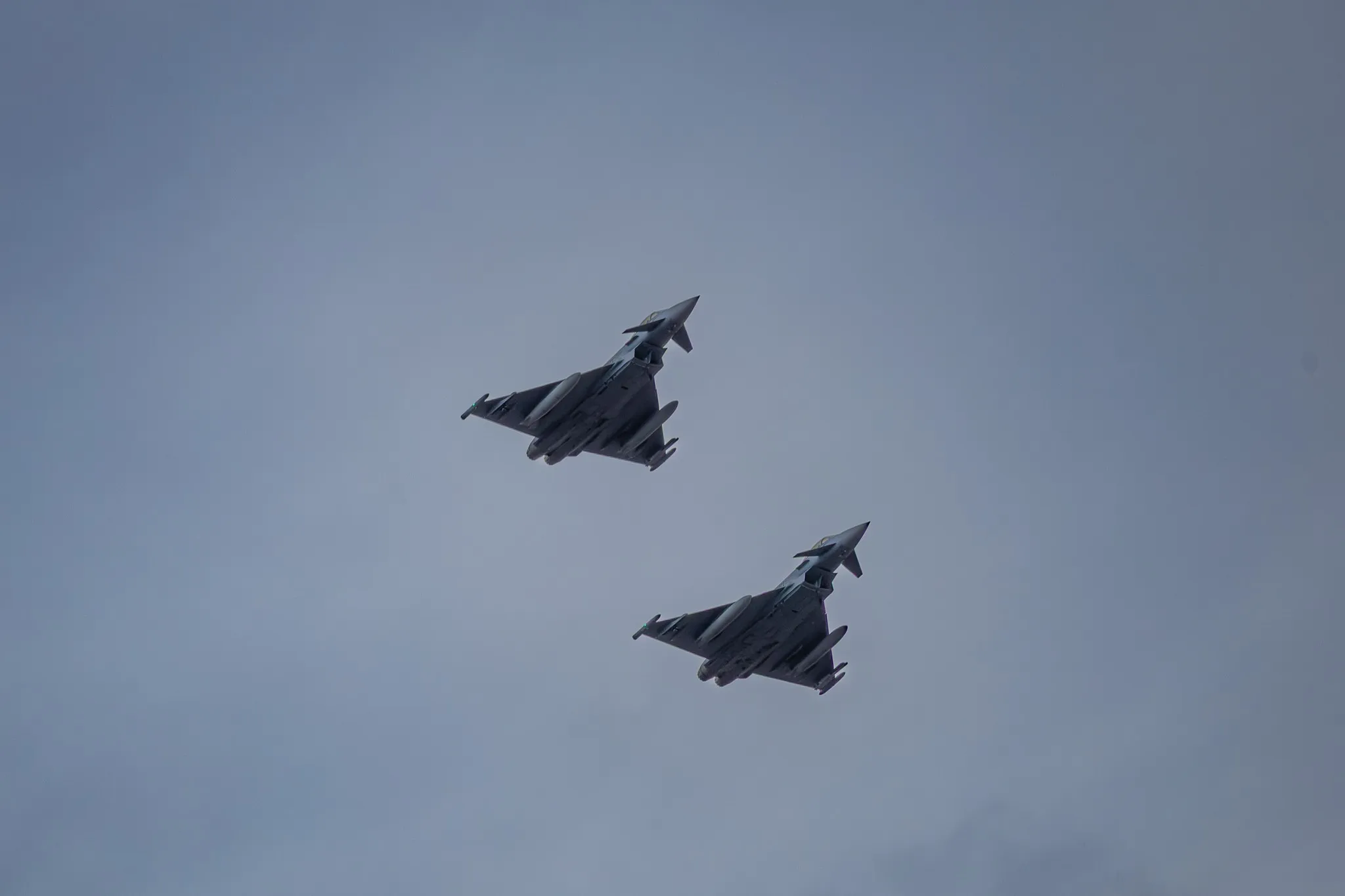 Zwei Eurofighter Typhoon in enger Staffelformation, Unteransicht vor grauem Himmel.